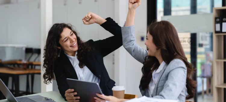 Due colleghe che festeggiano la conclusione di un lavoro portato a termine.